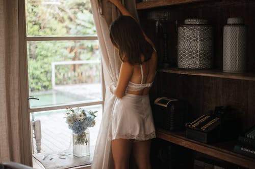 Woman in White Lingerie Standing Near Window