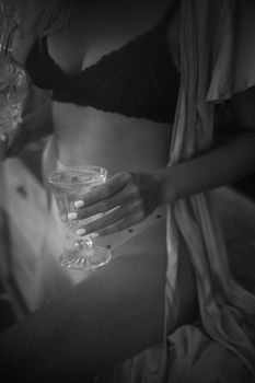 Elegant black and white photo of a woman in lingerie holding a drinking glass