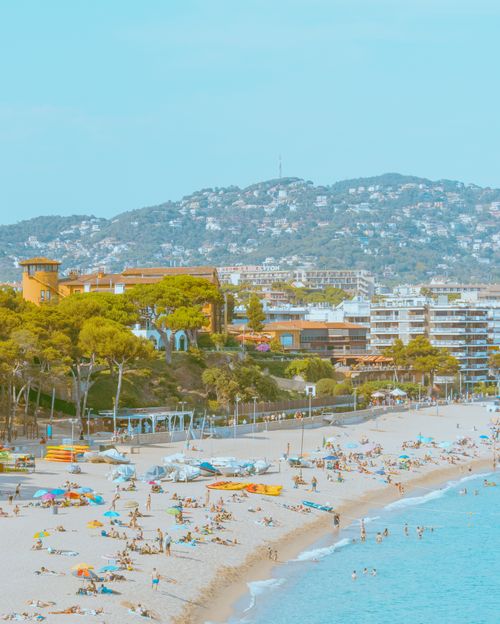 Free A vibrant beach scene with tourists relaxing by the sea in a coastal city on a sunny summer day. Stock Photo