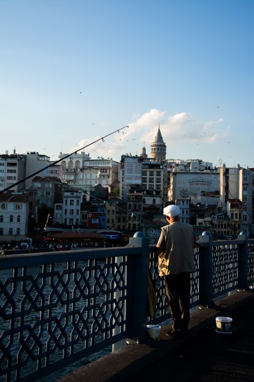 Free Back view of a fisherman on Galata Bridge, with Istanbul skyline and Galata Tower. Stock Photo