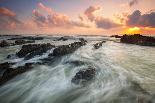 Pink Cloudy Sunset over Rocky Ocean