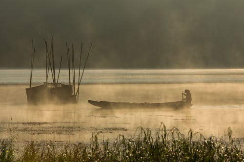 Man on Boat Sailing on Body of Water Near Fence during Daytime