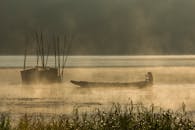 日出时分，渔民在薄雾笼罩的湖面上划船，呈现出一片宁静祥和的景象