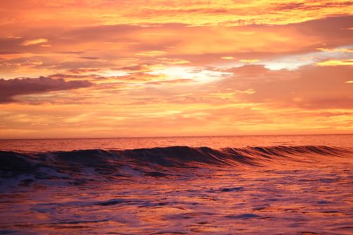 Free Stunning ocean sunset scene with vibrant clouds and dramatic waves, capturing nature's beauty. Stock Photo