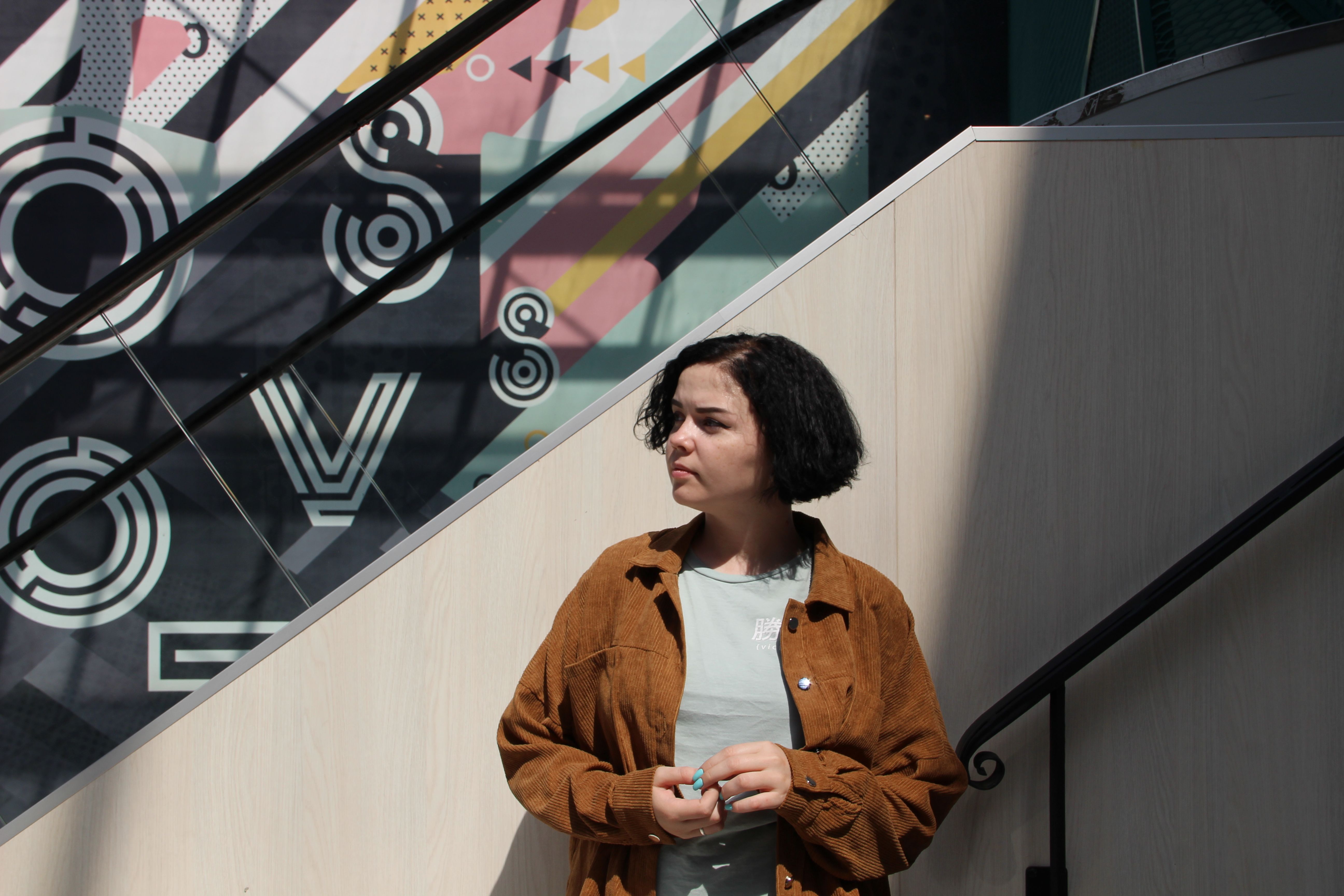 A Woman in Brown jacket Standing Beside the Stairs · Free Stock Photo