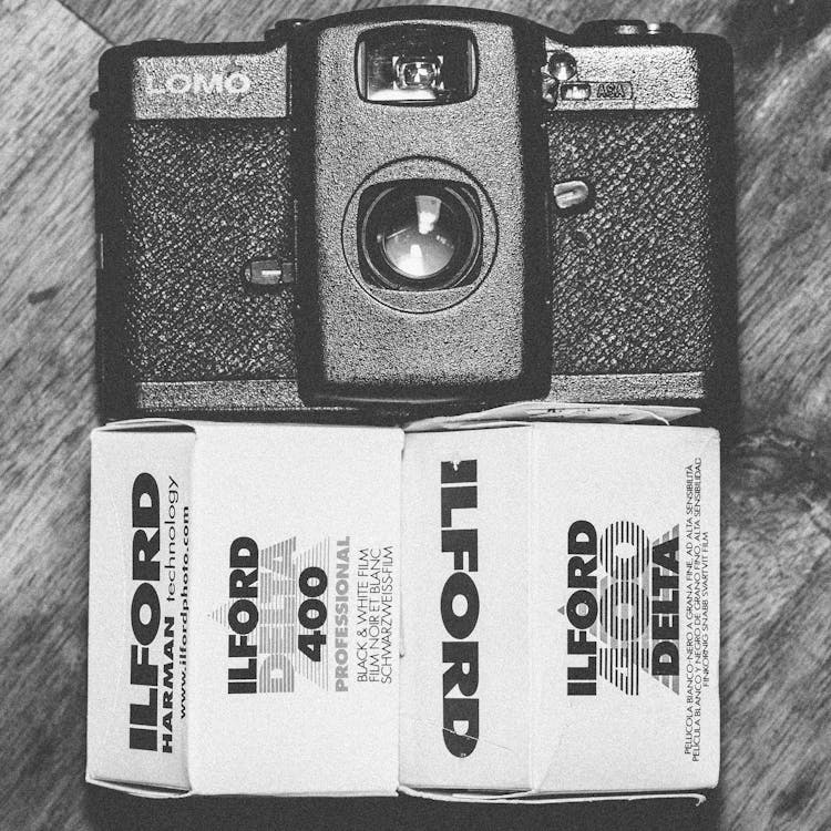 Ilford Delta 400 흑백 필름 박스 옆에있는 블랙 로모 컴팩트 카메라
