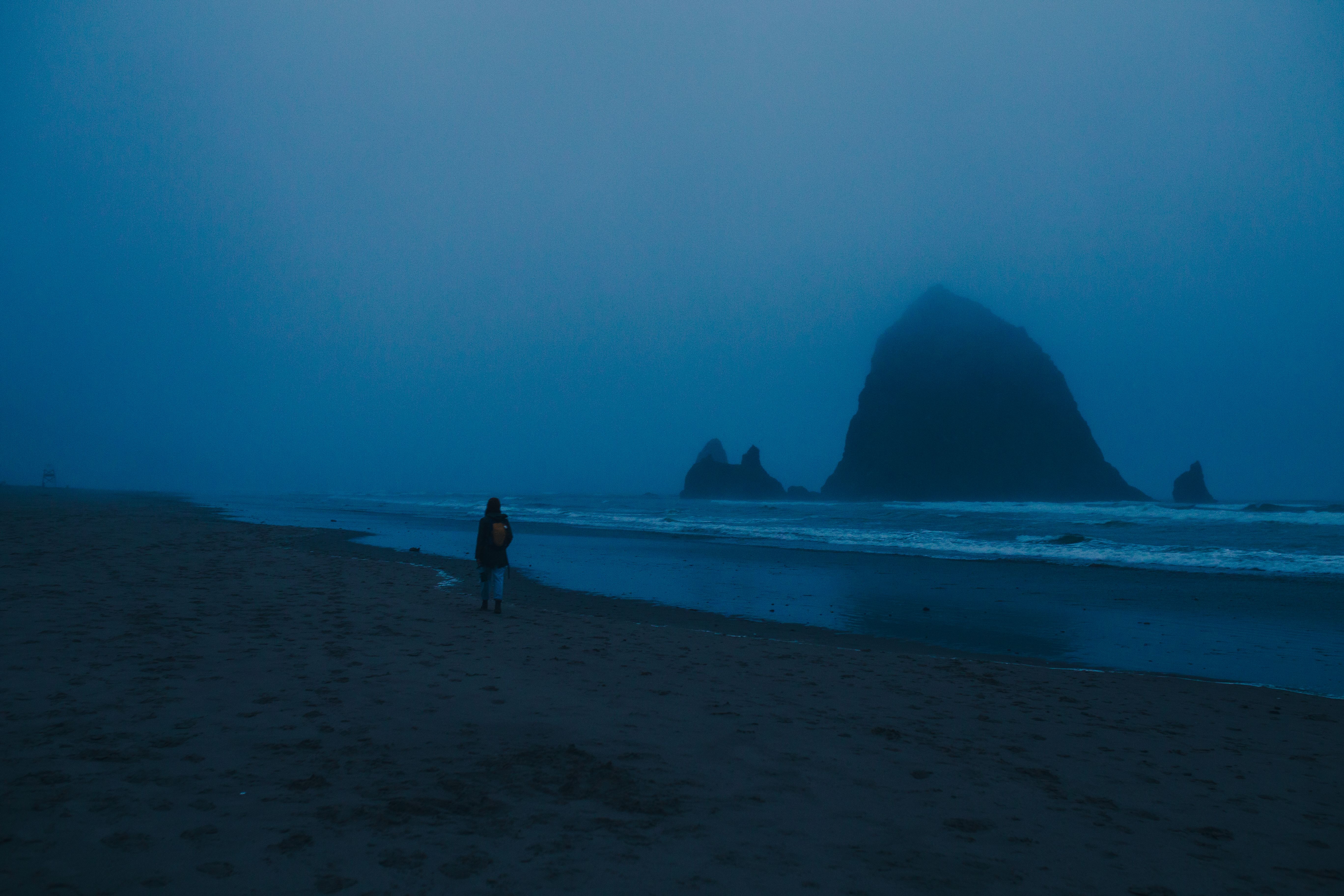 Person walking along Cannon Beach near Haystack Rock