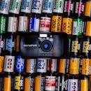 一台老式奥林巴斯相机被色彩缤纷的胶卷环绕，展现了摄影的怀旧之情