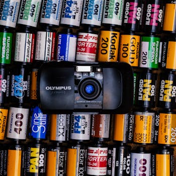 一台老式奥林巴斯相机被色彩缤纷的胶卷环绕，展现了摄影的怀旧之情