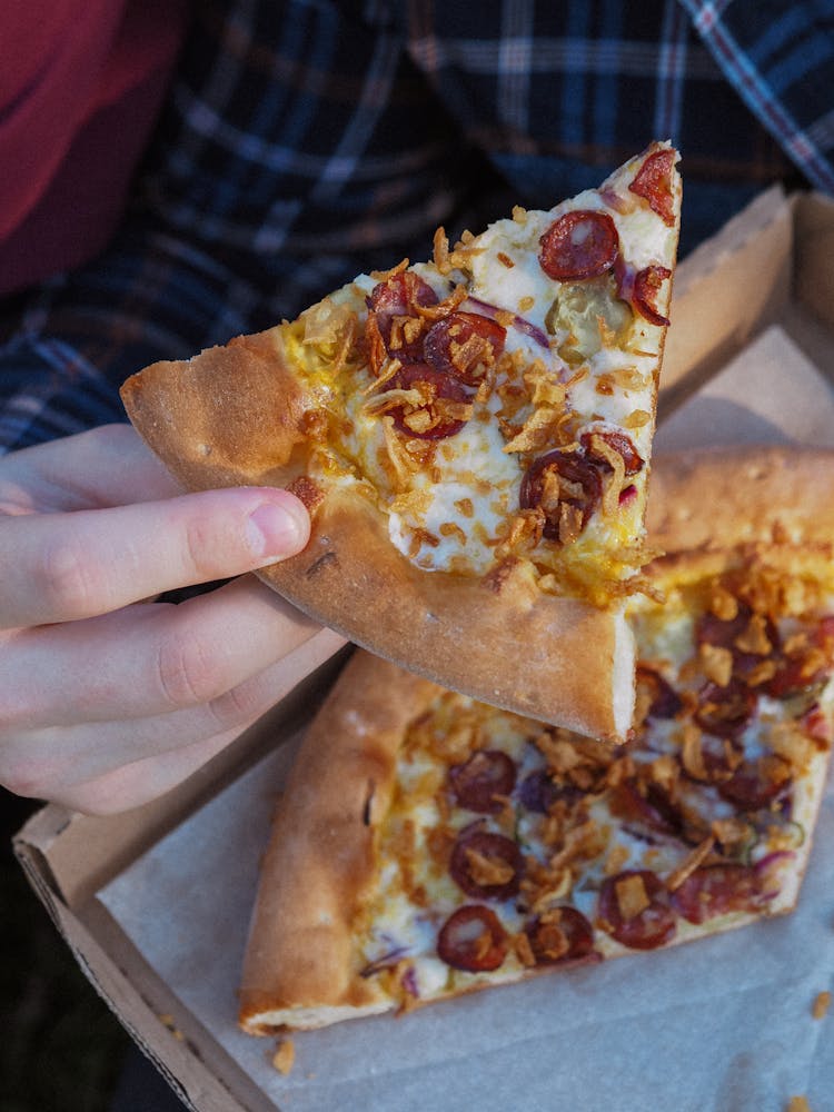 A Person Holding A Slice Of Pepperoni Pizza