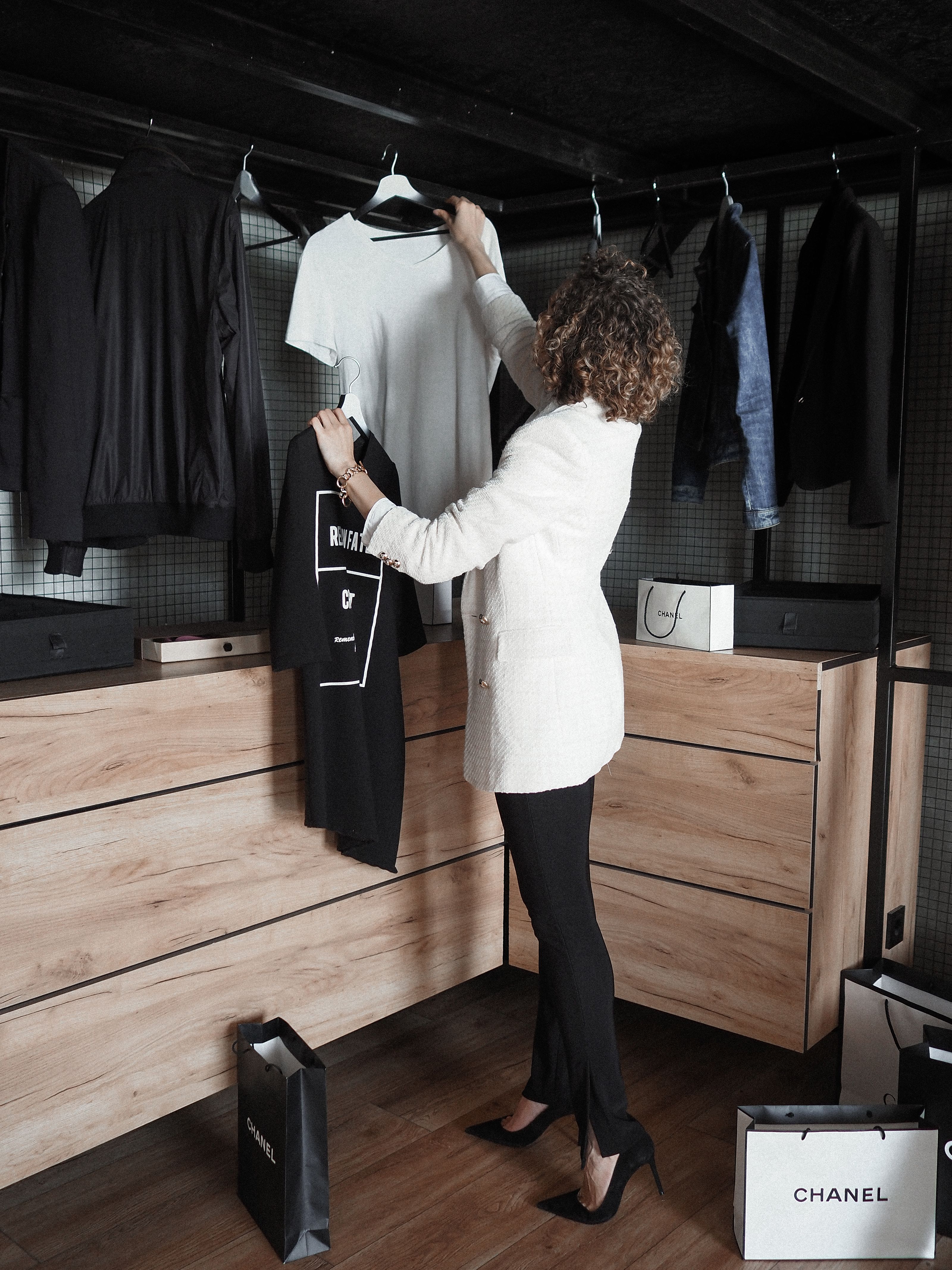 Uma mulher estilosa organizando roupas em um guarda-roupa moderno, destacando moda e design de interiores.