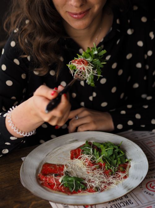Free A woman in a polka-dot blouse enjoys a fresh vegetarian salad at a cozy restaurant. Stock Photo
