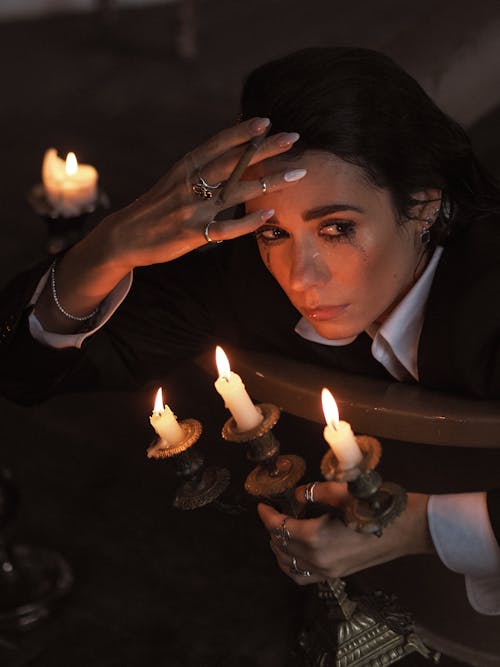 A Woman Holding Lighted Candles and a Cigarette Crying