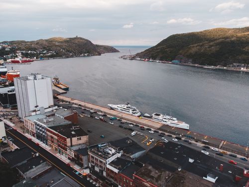 Free Aerial view of a bustling harbor with ships and a cityscape, set against rolling hills. Stock Photo