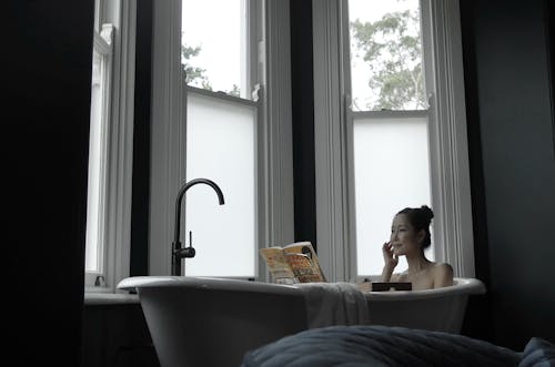 Free Woman in Bathtub Reading a Book Stock Photo