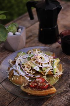 Authentic Mexican tostada with fresh toppings on rustic table setting in Puebla, Mexico.