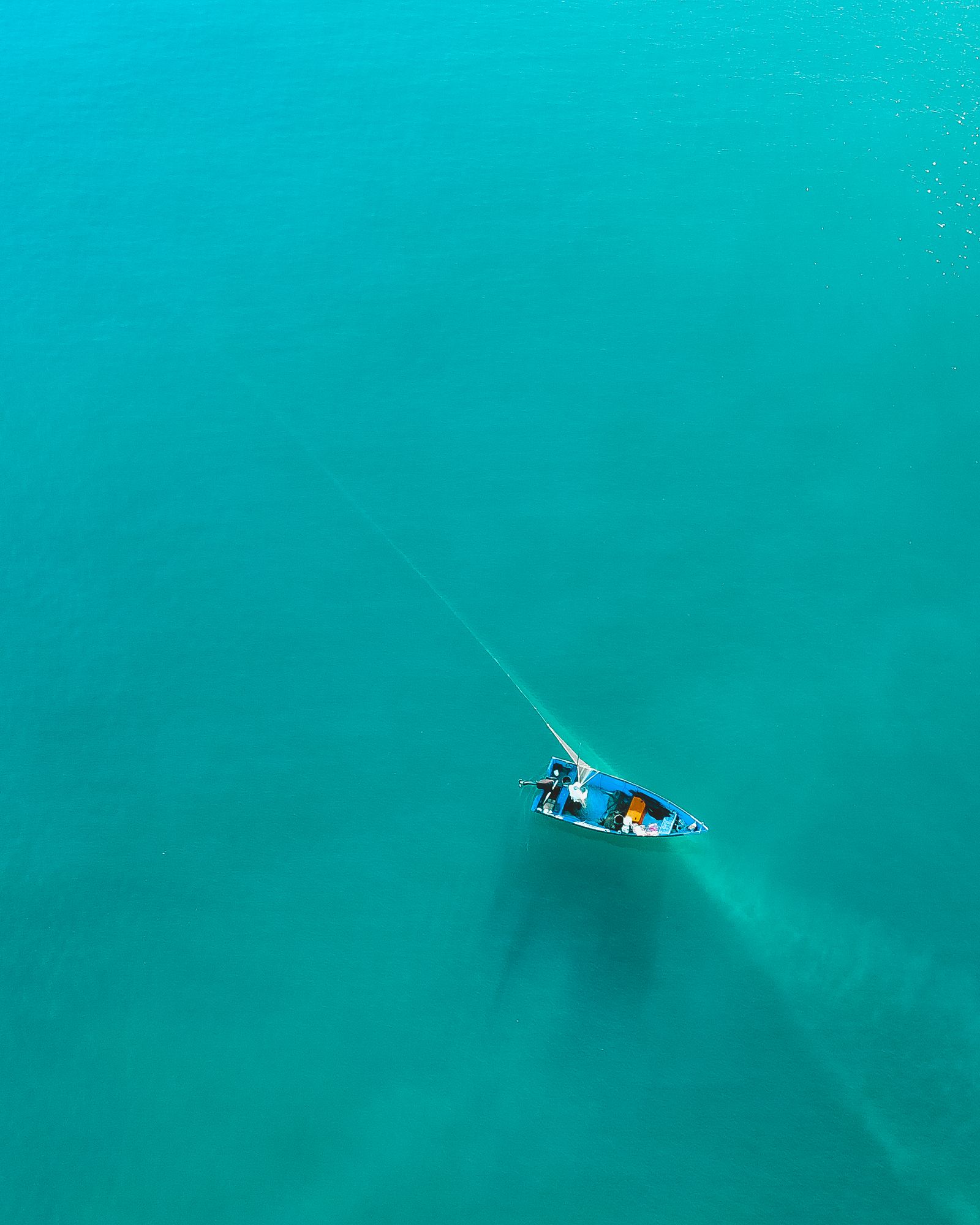 Drone view of a charter boat cutting across clear turquoise water