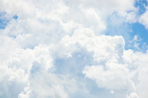 Free Bright, fluffy white clouds float in a vivid blue sky, capturing a serene summer day. Stock Photo