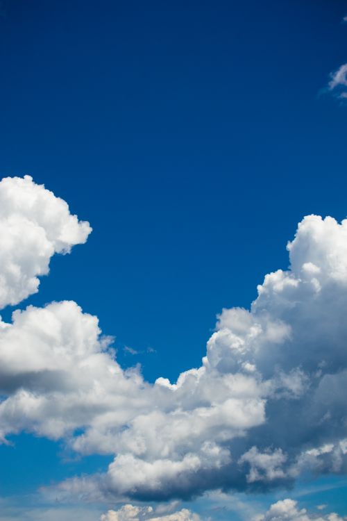Free A beautiful clear blue sky with soft, fluffy clouds, perfect for serene sceneries. Stock Photo