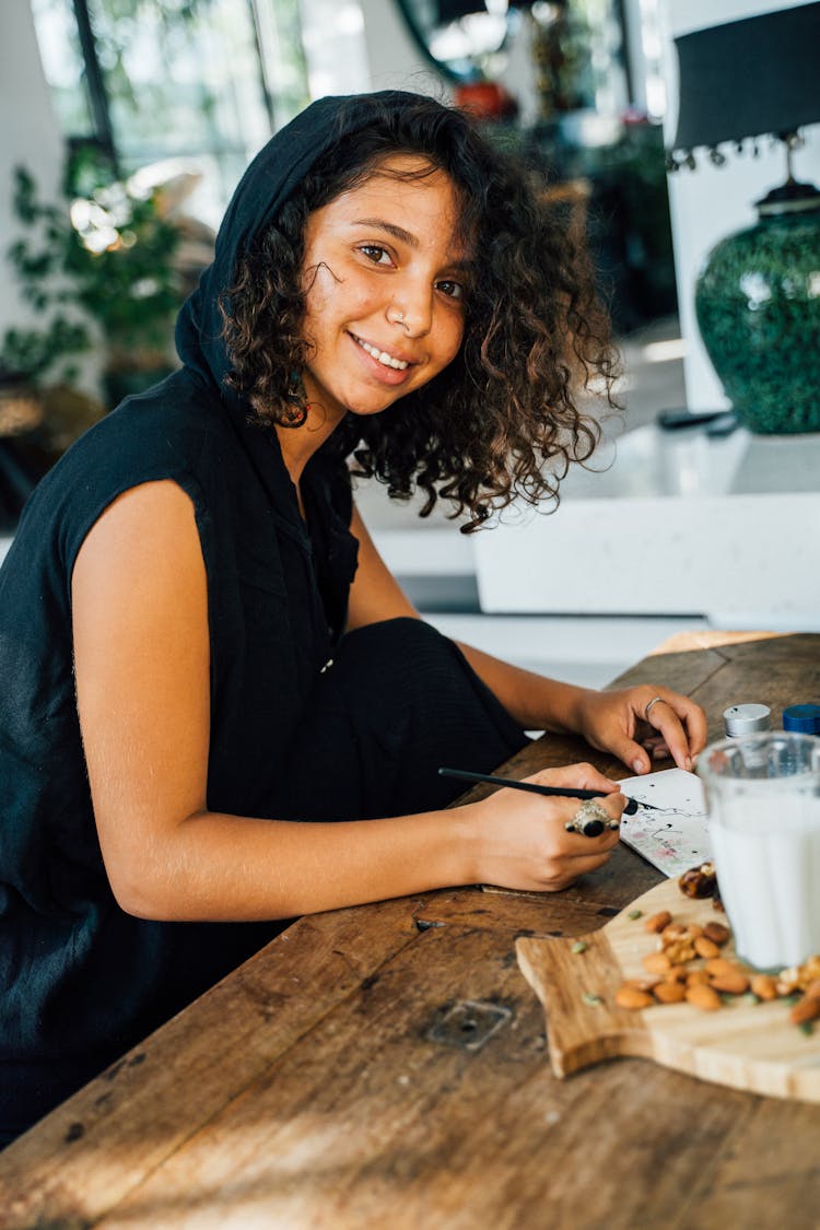 A Woman In Black Sleeveless Shirt Sitting Near The Wooden Table