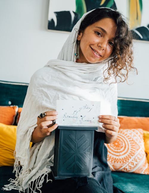 Free A Woman in White Headscarf Smiling while Holding a Paper Stock Photo