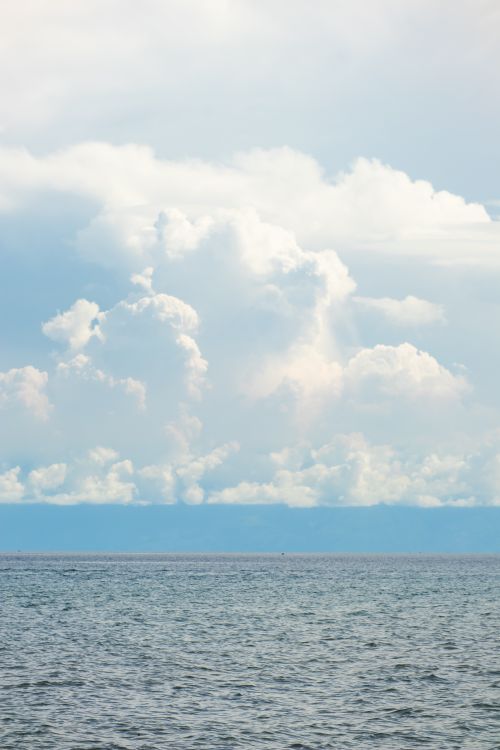 Free Serene seascape with expansive ocean and dramatic cloud formations. Stock Photo