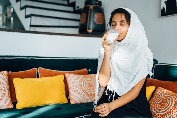 A Woman In A Hijab Drinking A Glass Of Milk 