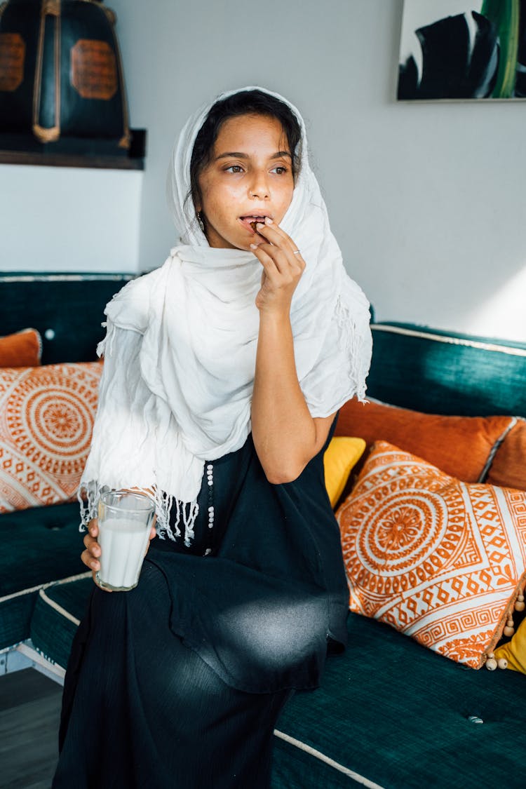 A Woman Sitting On The Couch While Eating Food