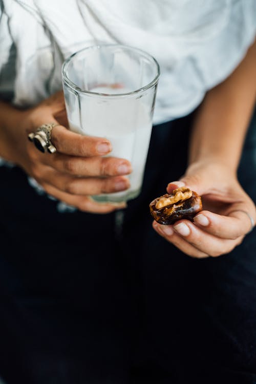 Person Holding Clear Drinking Glass Milk and Cookie