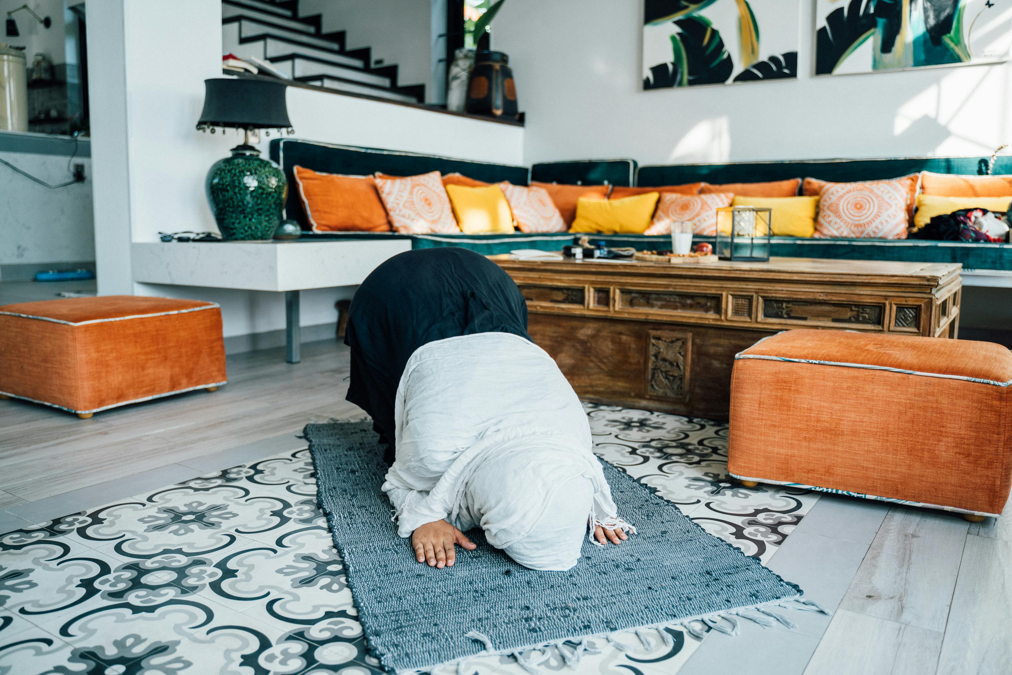 A Muslim woman in prayer indoors, showcasing Islamic faith and culture.