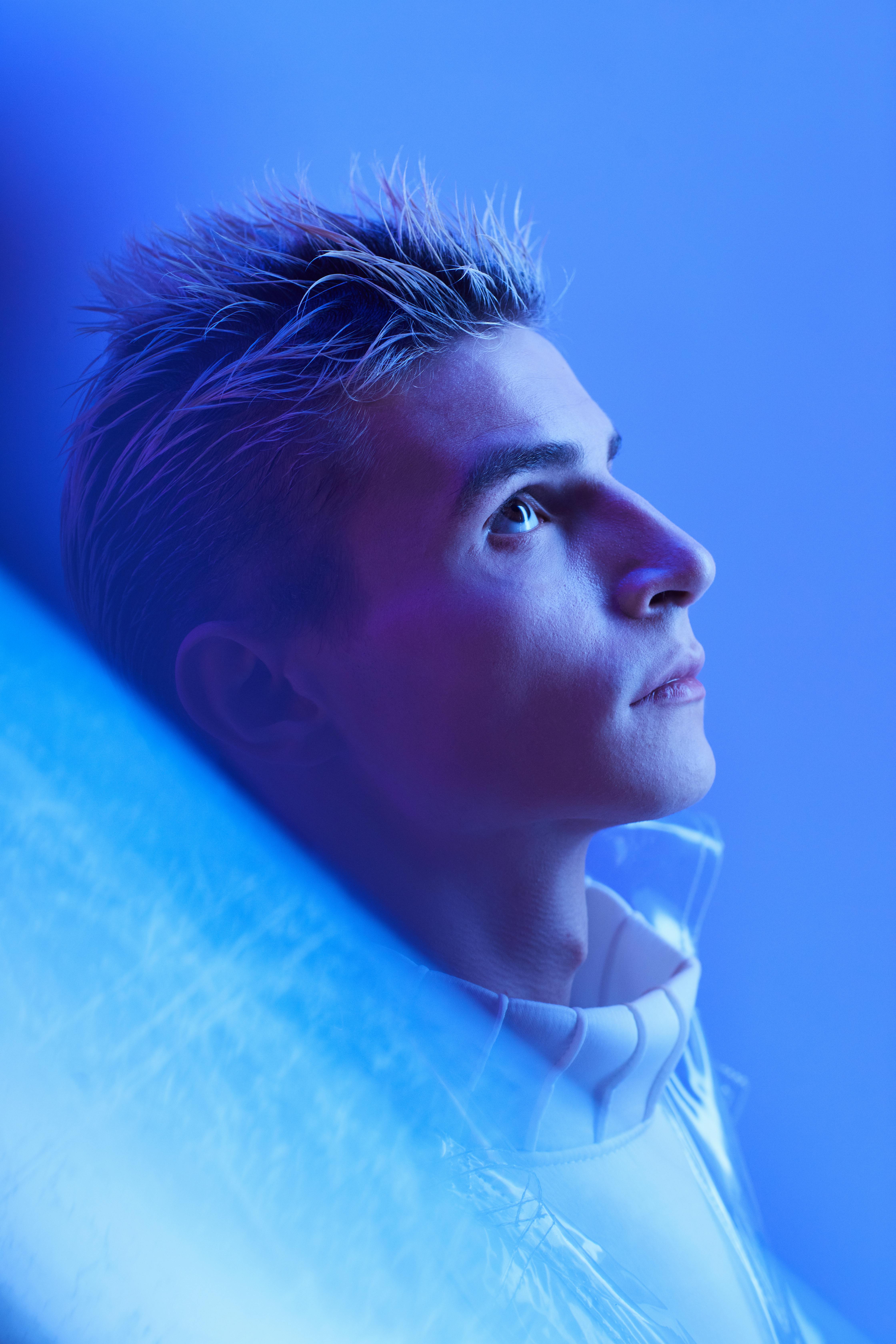 Conceptual portrait of a young man with blue lighting and futuristic elements.