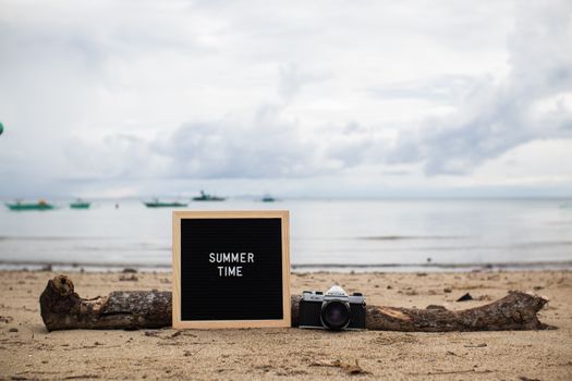 Beach scene with a message board reading 'SUMMER TIME' and a vintage camera.