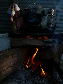 A cooking pot over an open wood fire, capturing the essence of outdoor cooking in a rustic setting.