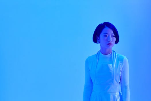 Conceptual portrait of an Asian woman in blue lighting, expressing futuristic themes.