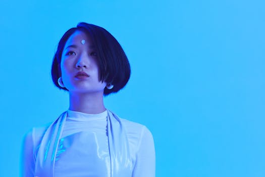 Stylish asian woman in futuristic fashion with a blue backdrop.