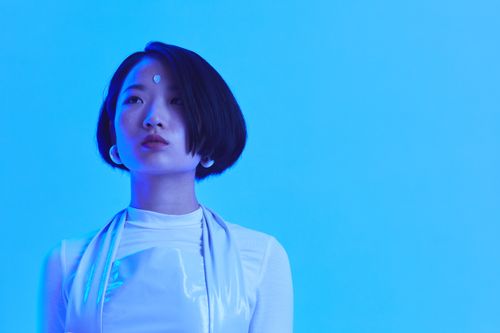 Free Stylish asian woman in futuristic fashion with a blue backdrop. Stock Photo
