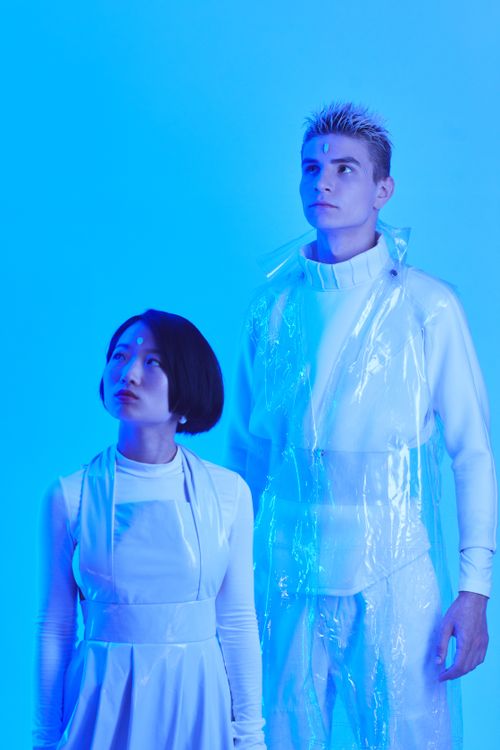 Free Futuristic fashion portrait of a woman and man in avant-garde attire against a blue background. Stock Photo