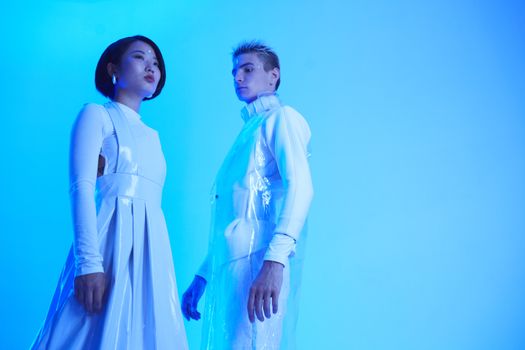 Stylish futuristic fashion shoot with modern attire in a blue-lit studio.
