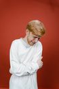 Man in White Long Sleeve Shirt Standing Near Red Wall and Crying