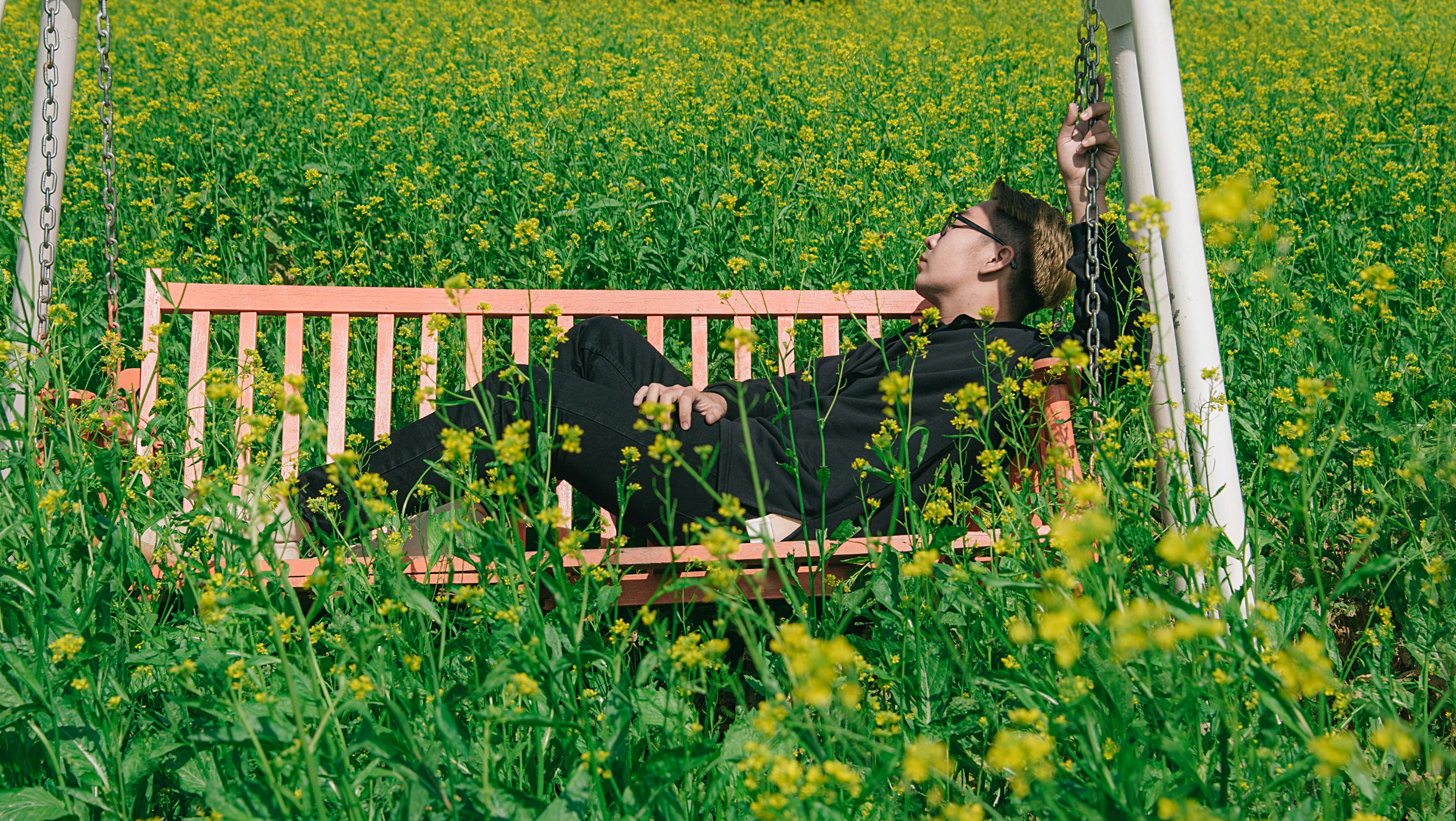 man in white and brown canopy swing surrounded with yellow petal flower