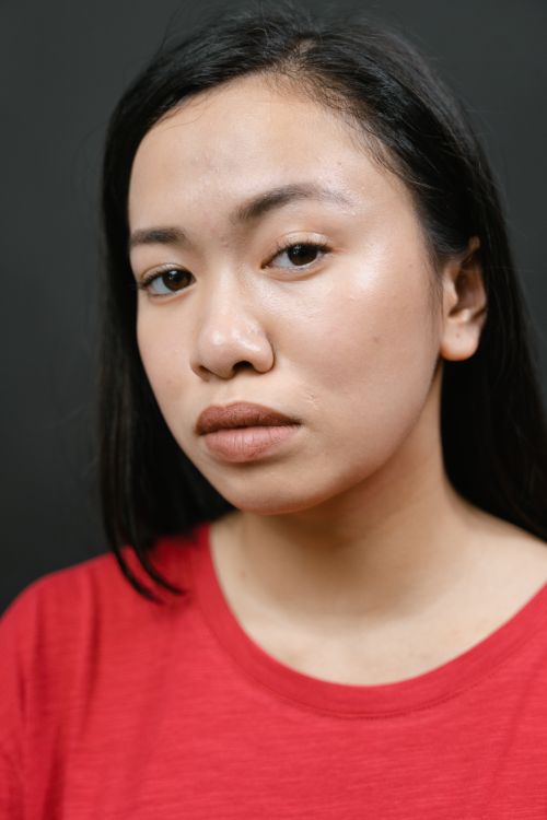Free Close-up portrait of a woman in a red shirt expressing a neutral mood during a studio session. Stock Photo