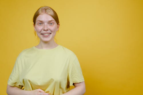 A  Woman in Yellow Crew Neck T-shirt Standing Beside a Yellow Wall