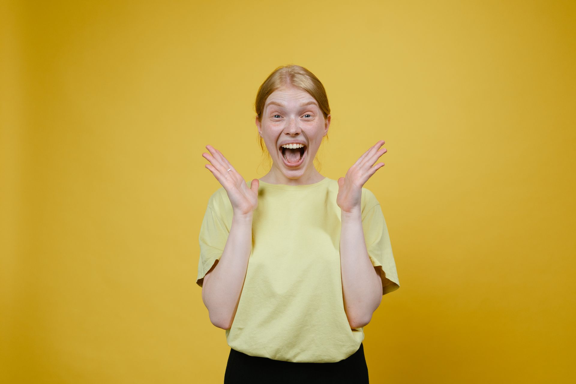 Woman in Yellow T-shirt and Black Pants Standing Excited with Open Mouth