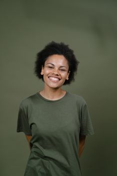 Portrait of a cheerful African American woman with afro hair smiling against a green background.