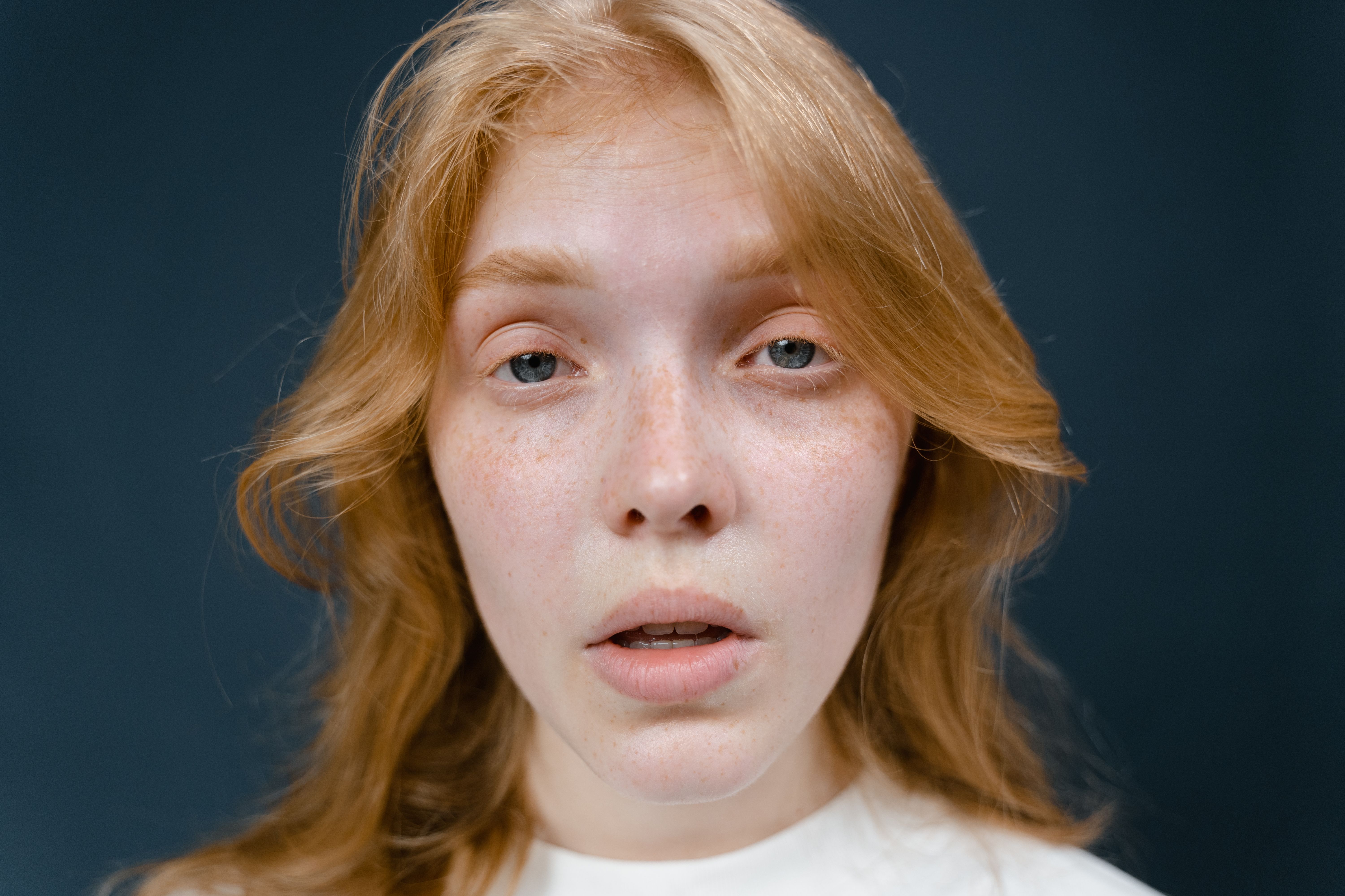 woman applying a calming face serum to redness-prone skin in a bright bathroom
