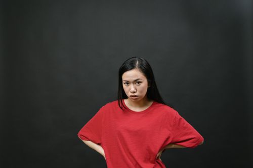 Free Studio portrait of a confident woman in a red shirt posing fiercely against a black background. Stock Photo