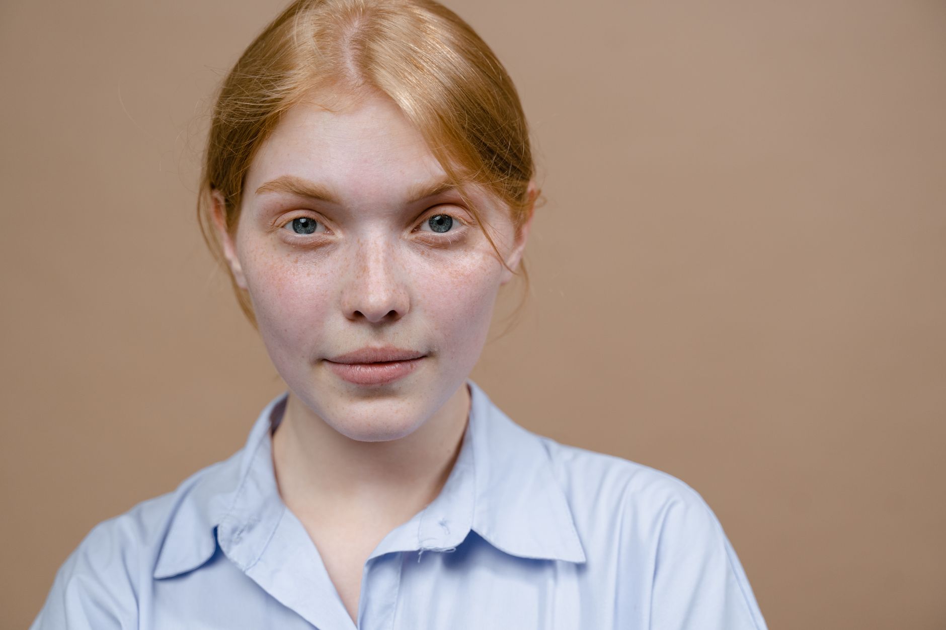 close-up of woman with visible facial redness and rosacea-prone skin applying skincare serum