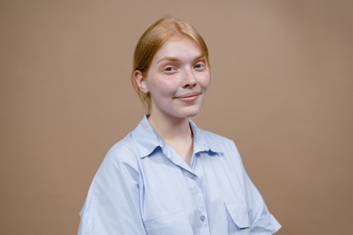 Free A portrait of a smiling young woman with a neutral background, ideal for lifestyle content. Stock Photo