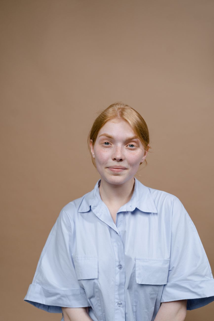Portrait of a young woman smiling gently in a light shirt against a beige backdrop.