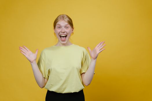 Excited woman expressing happiness against a bright yellow backdrop, showcasing energy and positivity.